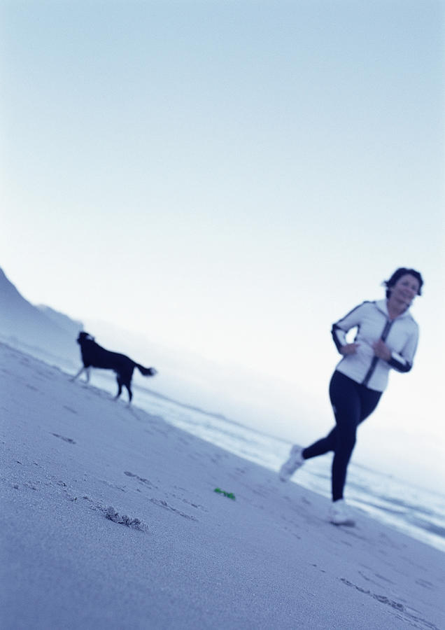 Mature woman running on beach Photograph by Vincent Hazat