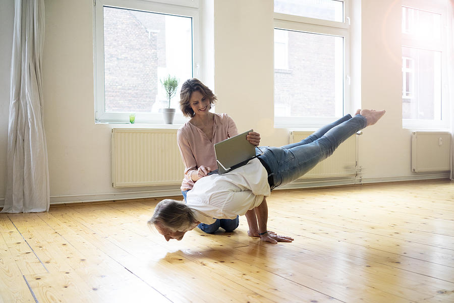 Mature woman using tablet on back of man doing a handstand Photograph by Westend61