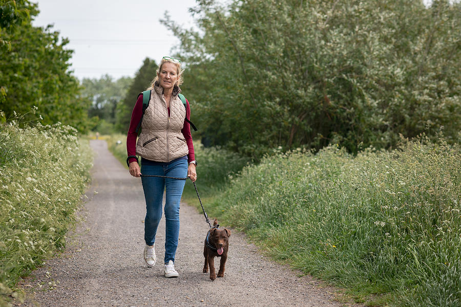 Mature Woman Walking Her Patterdale Terrier Photograph by SolStock