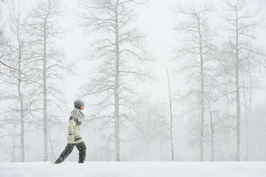 Mature woman walking in snow Photograph by Thomas Northcut