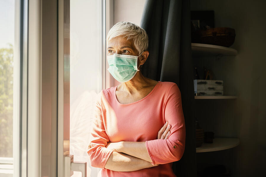 Mature woman wearing surgical mask Photograph by Vesnaandjic