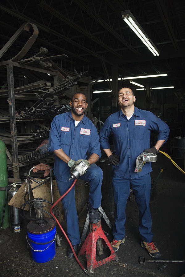 Mechanics working together in repair shop Photograph by Jon Feingersh Photography Inc