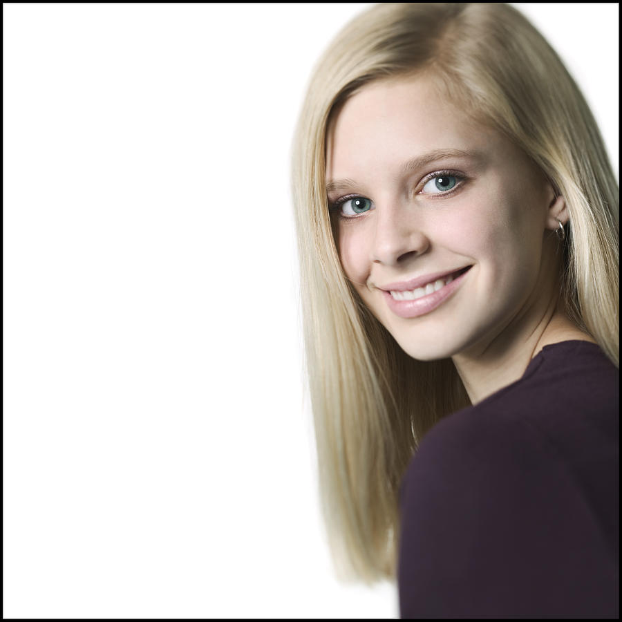 Medium Close Up Shot Of A Teenage Female In A Purple Shirt As She Looks Over Her Shoulder And Smiles Photograph by Photodisc