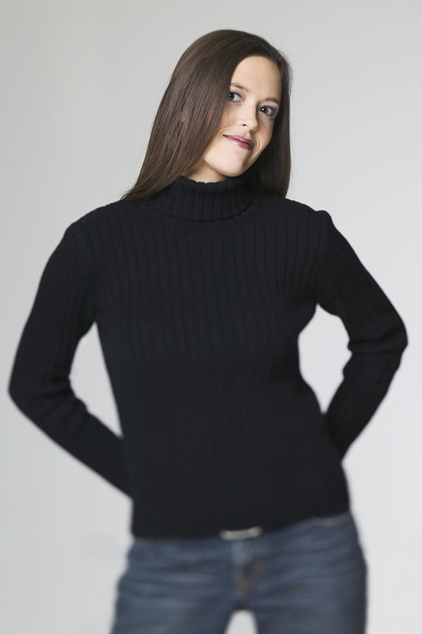 Medium Shot Of A Young Adult Woman In A Black Sweater As She Puts Her Hands On Her Hips And Smiles Photograph by Photodisc