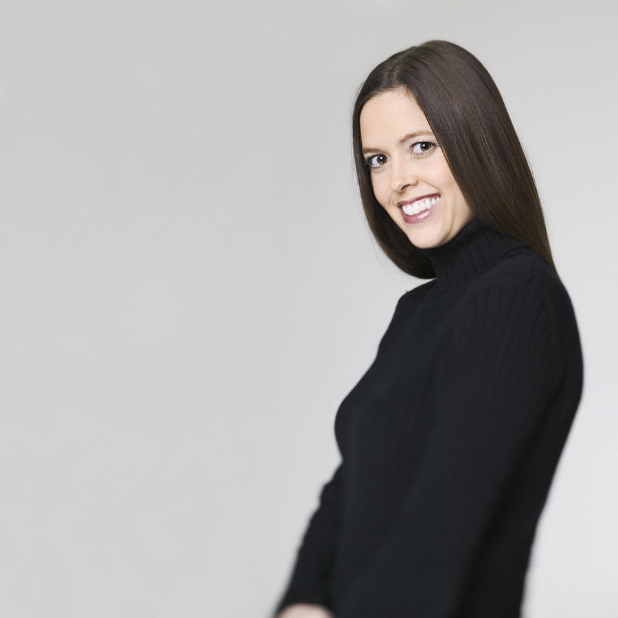 Medium Shot Of A Young Adult Woman In A Black Sweater As She Turns And Smiles Photograph by Photodisc