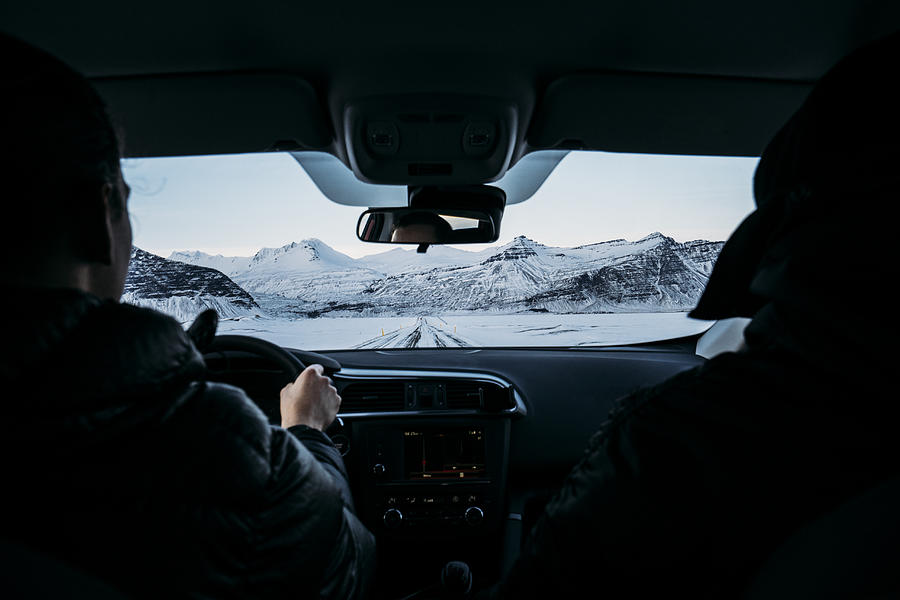 Men driving car through snow covered landscape, Iceland Photograph by Caia Image