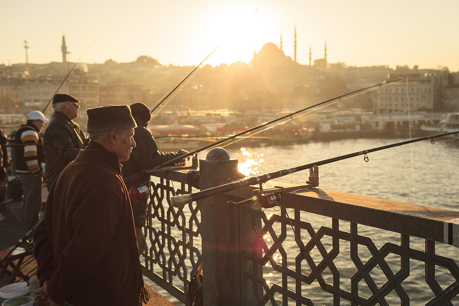 Men fishing at sunset on the Galata Bridge, Istanbul, Turkey Photograph by Kelvinjay