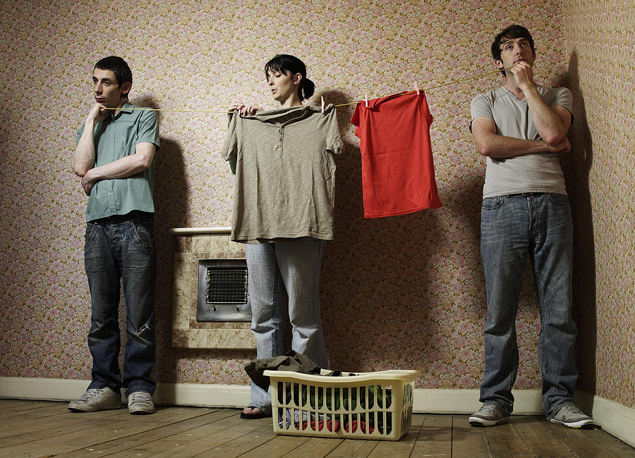Men holding washing line for woman Photograph by Simon Bremner