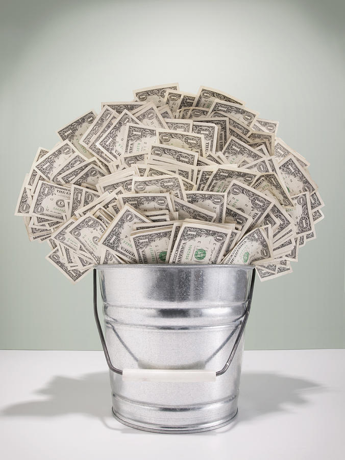 Metal bucket filled with US $1 bills Photograph by PM Images