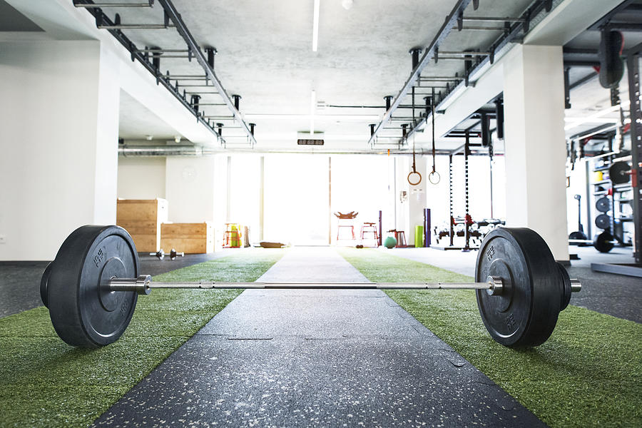 Metal heavy barbell laid on the floor in modern gym. Photograph by GrapeImages Metal heavy barbell laid on the floor in modern gym. Photograph by GrapeImages