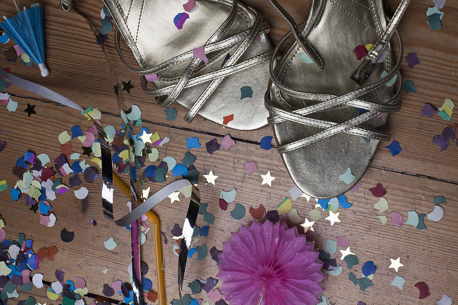 Metallic strappy heels, confetti and streamers littering a hardwood floor Photograph by Larry Washburn