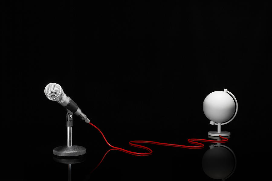 Microphone in a desktop stand connecting to a white globe on a tabletop Photograph by Creative Crop