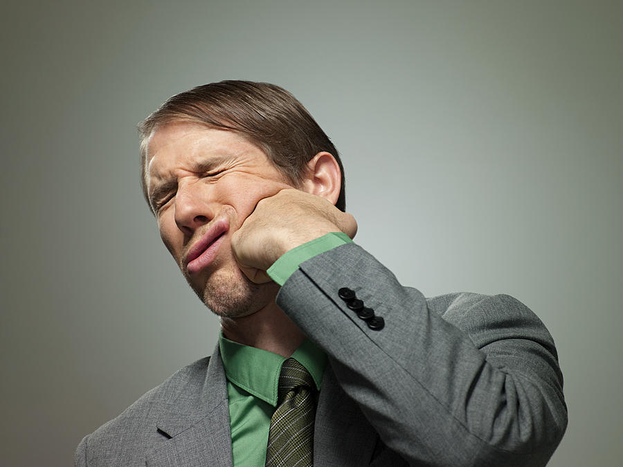 Mid adult businessman punching himself in face, portrait Photograph by Image Source
