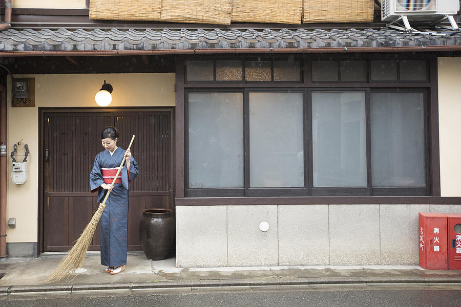 Mid Adult Japanese woman in kimono sweeping with broom Photograph by Imagenavi