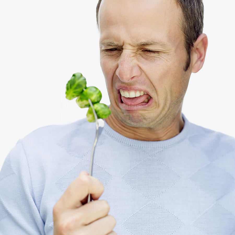 mid adult man making a face in front of a fork with Brussels sprouts Photograph by Stockbyte