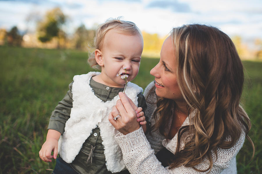 Mid adult woman holding up daisy for toddler daughter in field Photograph by Cultura RM Exclusive/Erin Lester Mid adult woman holding up daisy for toddler daughter in field Photograph by Cultura RM Exclusive/Erin Lester