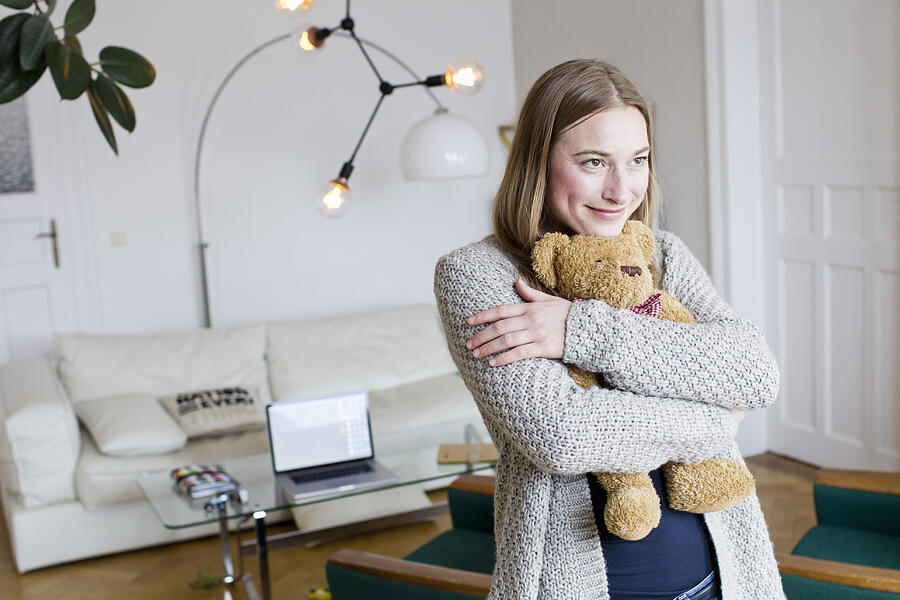 Mid adult woman hugging teddy bear in living room Photograph by Emely