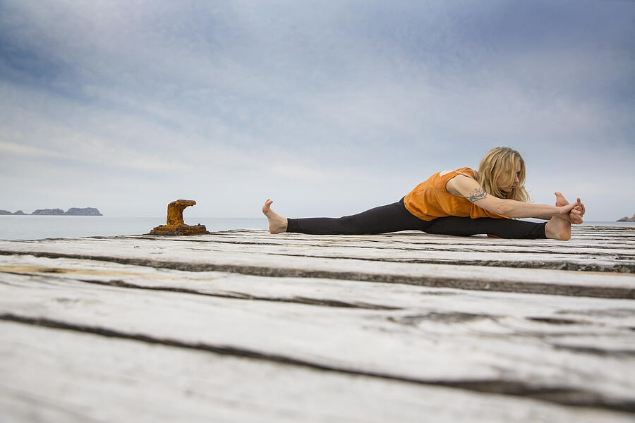 Mid adult woman practicing yoga on wooden sea pier Photograph by Russ Rohde