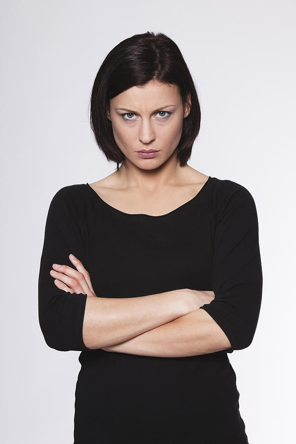 Mid adult woman with arms crossed and staring against white background Photograph by Westend61