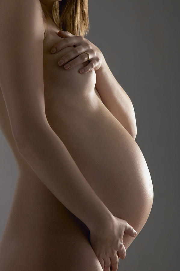 Mid Section of a Naked Pregnant Woman With Her Arm Around Her Stomach Photograph by Nick White
