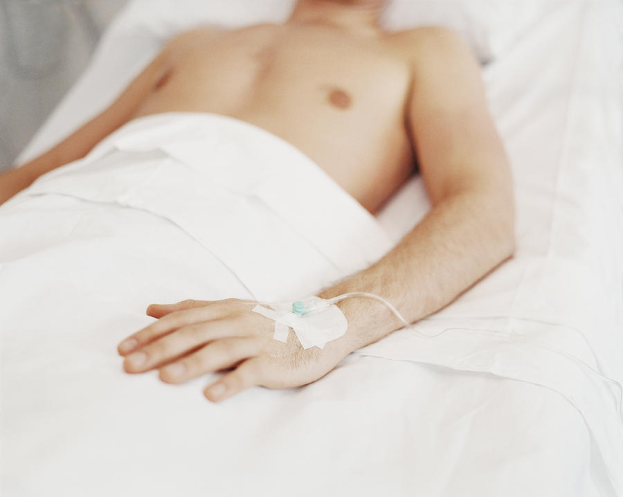 Mid Section of a Young Man Lying in a Hospital Bed with a Tube in His Hand Photograph by Janie Airey