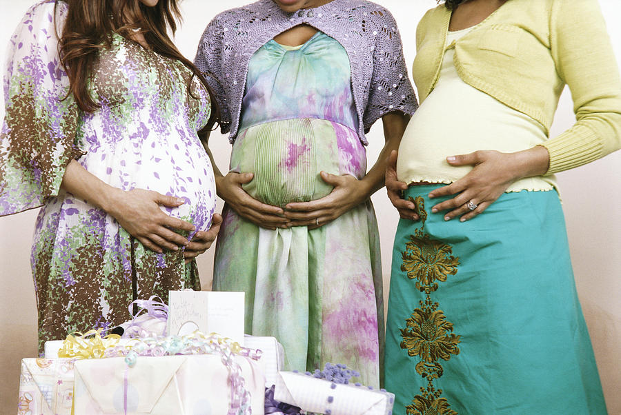 Mid Section of Three Pregnant Women Standing by a Pile of Gifts, Holding Their Stomachs Photograph by Nancy Ney