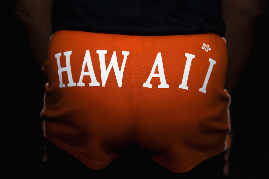 Mid section view of a person wearing shorts with Hawaii printed on it Photograph by Glowimages