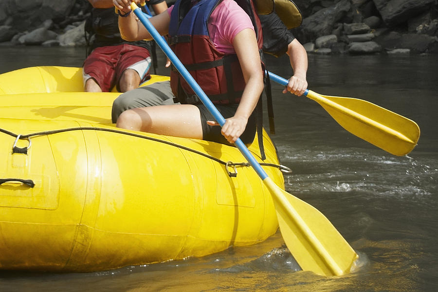 Mid section view of three people rafting in a river Photograph by Glowimages