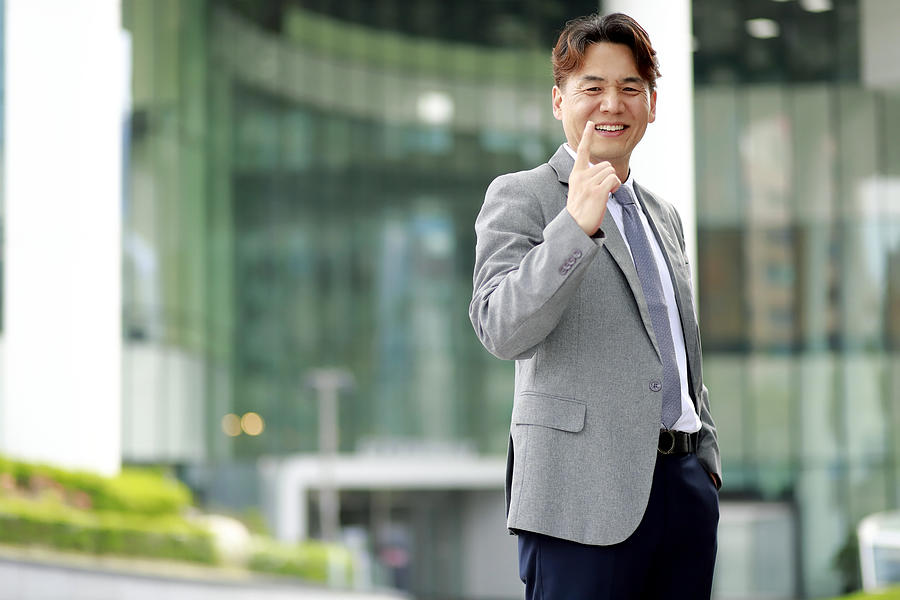Middle aged businessman pointing finger outdoors Photograph by Runstudio