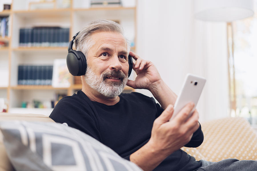 Middle-aged man listening to music online at home Photograph by Stockfour