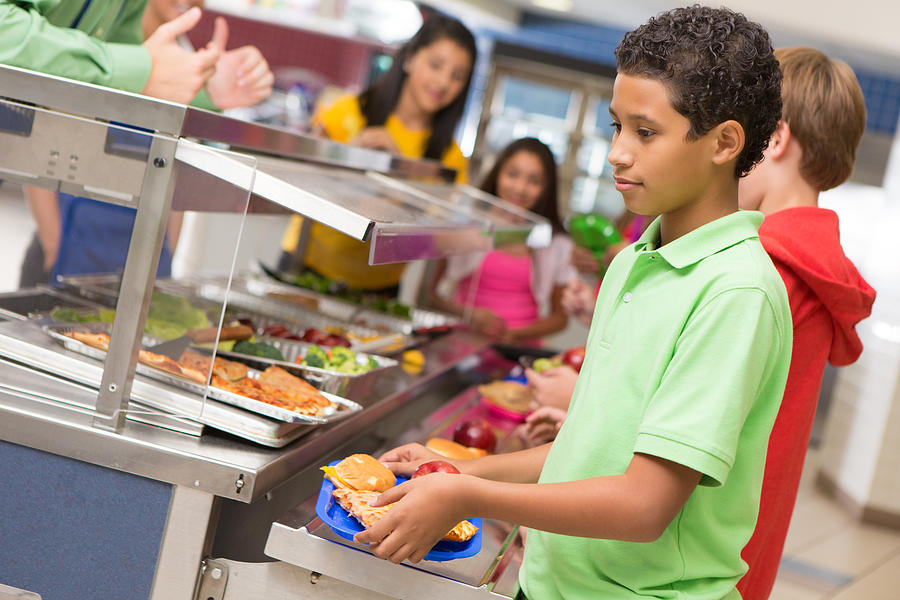 Middle school students getting lunch items in cafeteria line Photograph by SDI Productions
