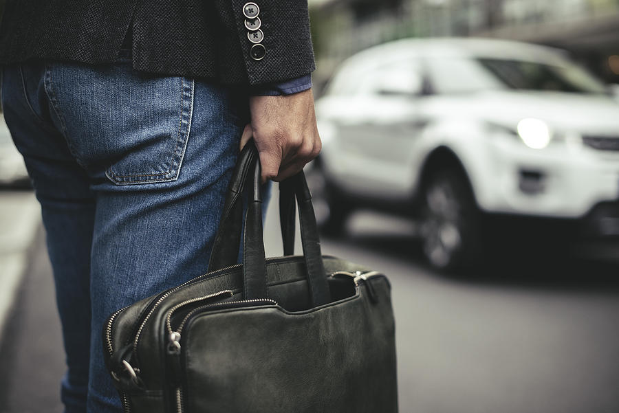 Midsection of businessman carrying briefcase on street Photograph by Maskot