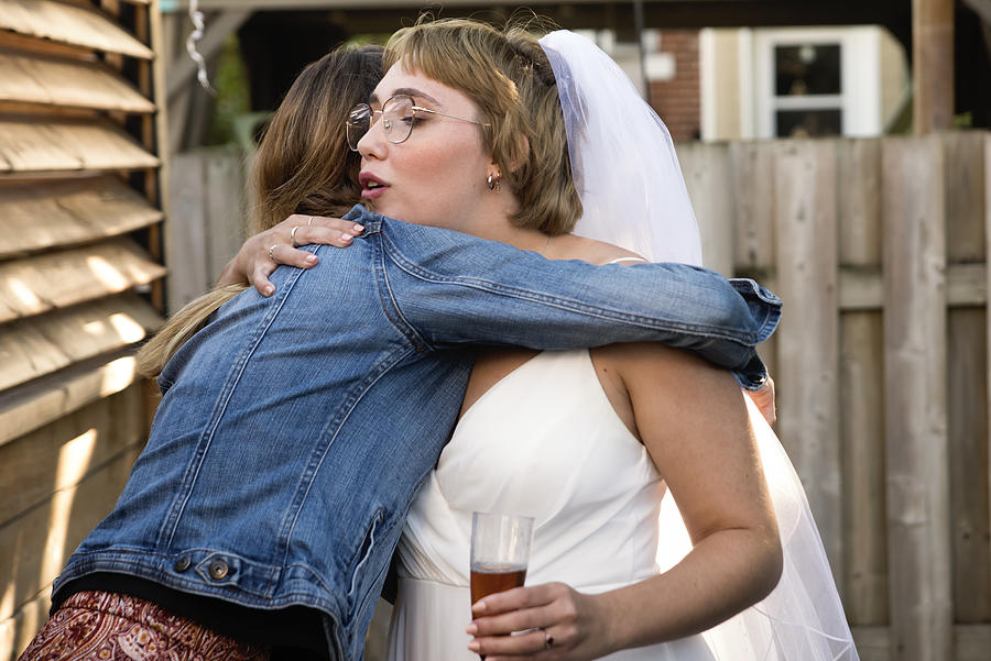 Millennial bride hugging godmother at wedding cocktail in backyard. Photograph by Martinedoucet