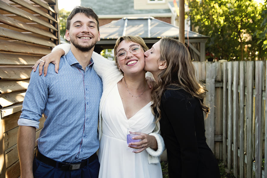 Millennial bride posing with brother and sister in backyard. Photograph by Martinedoucet