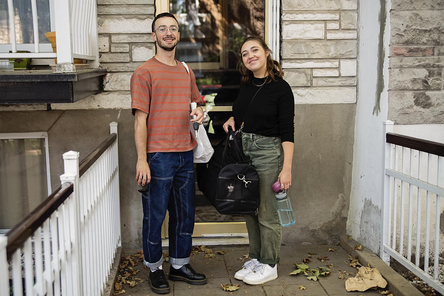 Millennial couple and newly adopted kitten in pet carrier at home. Photograph by Martinedoucet