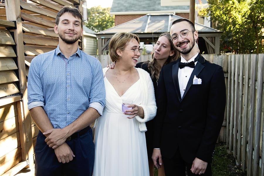 Millennial newlywed couple posing with brother and sister in backyard. Photograph by Martinedoucet