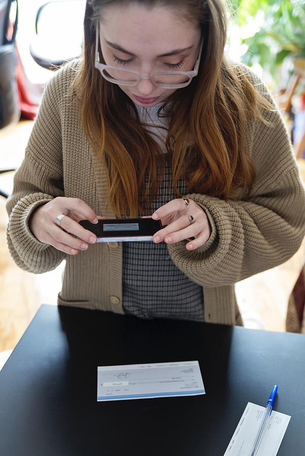 Millennial woman using digital banking to make a deposit. Photograph by Martinedoucet