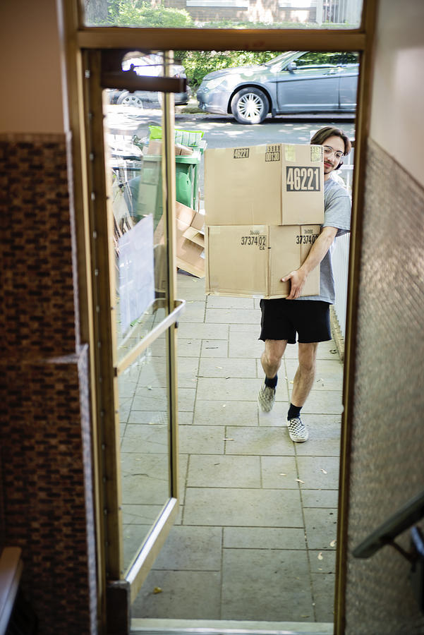 Millennial young man moving in new apartment. Photograph by Martinedoucet