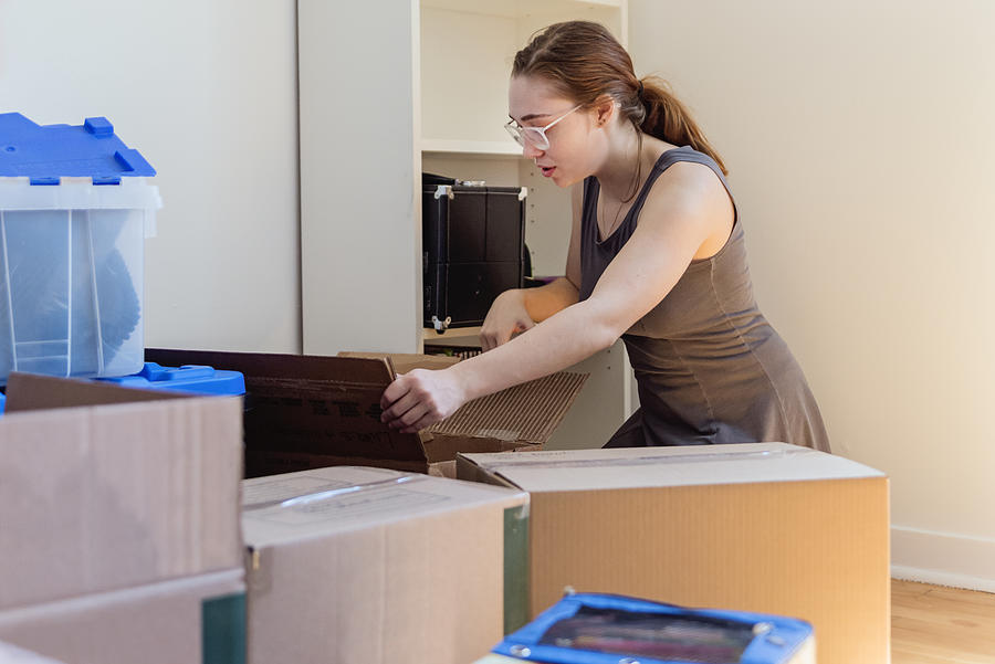 Millennial young woman moving in new apartment. Photograph by Martinedoucet