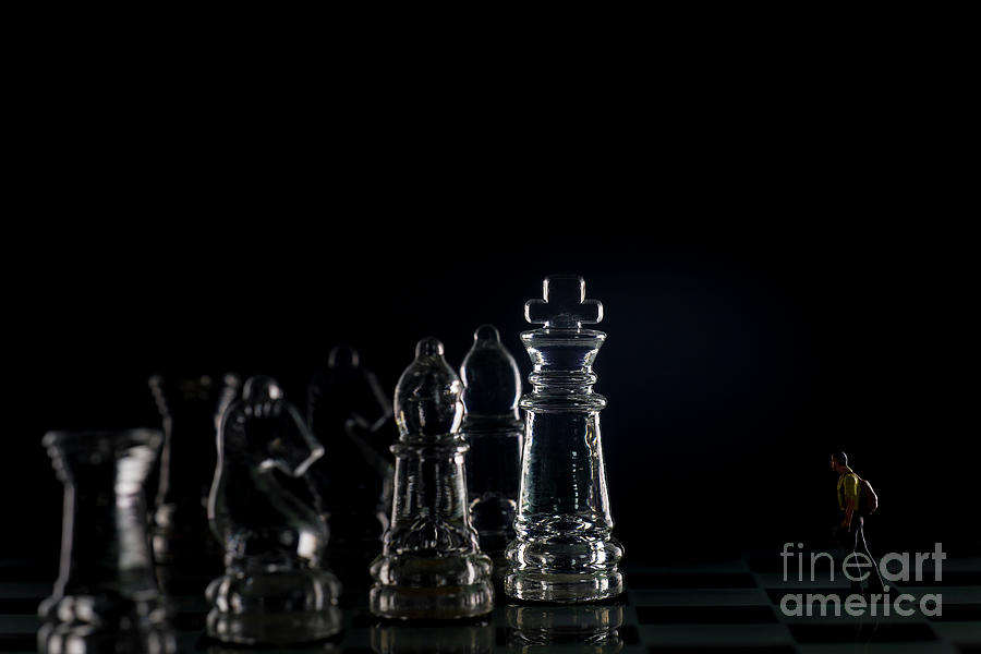 Miniature figure people as businessman standing face to face with King chess piece on chessboard. macro Photograph by Pablo Avanzini
