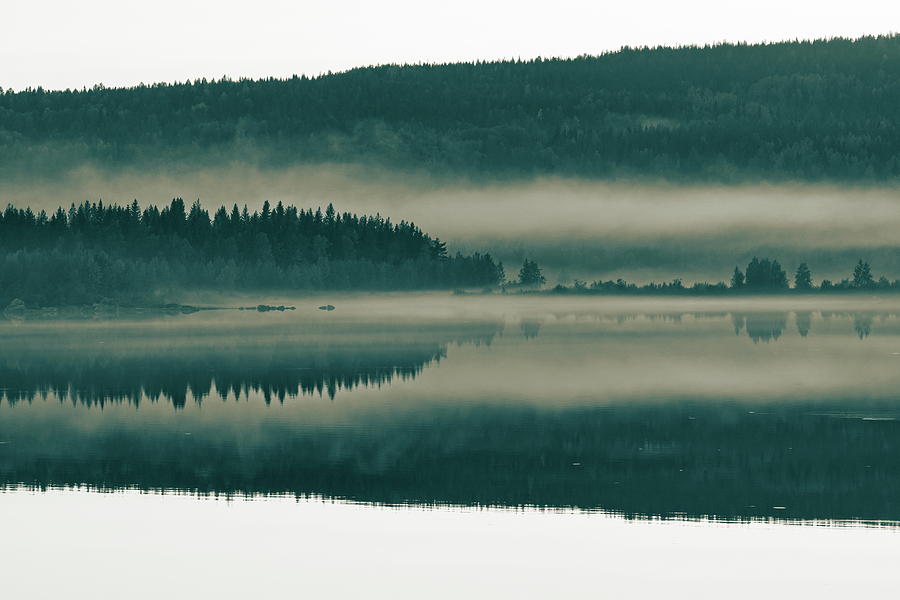 Mist is rising from the wooded shore of a smooth lake at dusk -  Photograph by Ulrich Kunst And Bettina Scheidulin