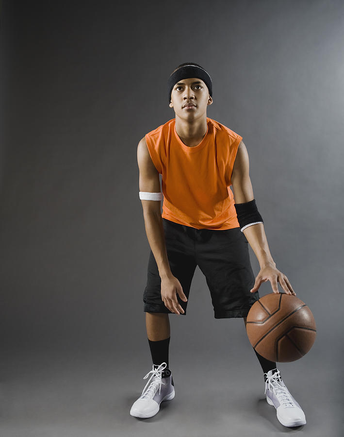 Mixed race basketball player dribbling basketball Photograph by Erik Isakson