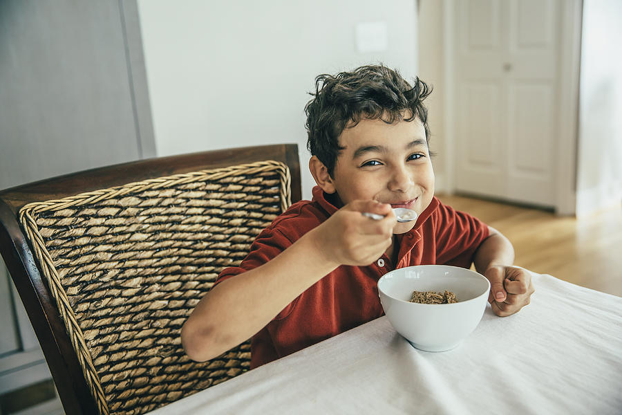 Mixed race boy eating cereal at table Photograph by Inti St Clair