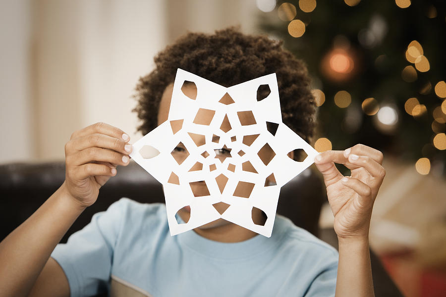 Mixed race boy holding paper snowflake Photograph by Hill Street Studios