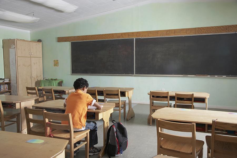 Mixed Race boy in empty classroom Photograph by Blend Images - Tanya Constantine