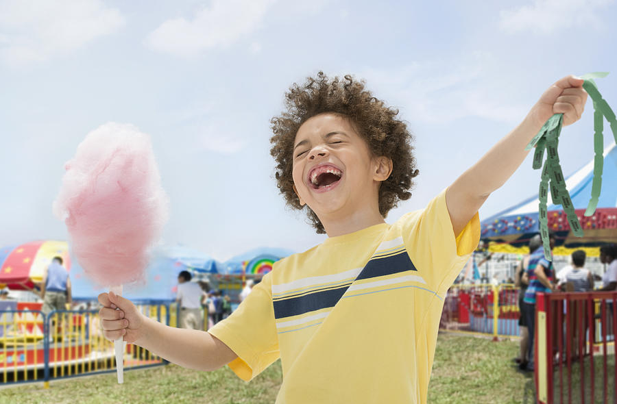 Mixed race boy with cotton candy and prize tickets at fair Photograph by Jose Luis Pelaez Inc