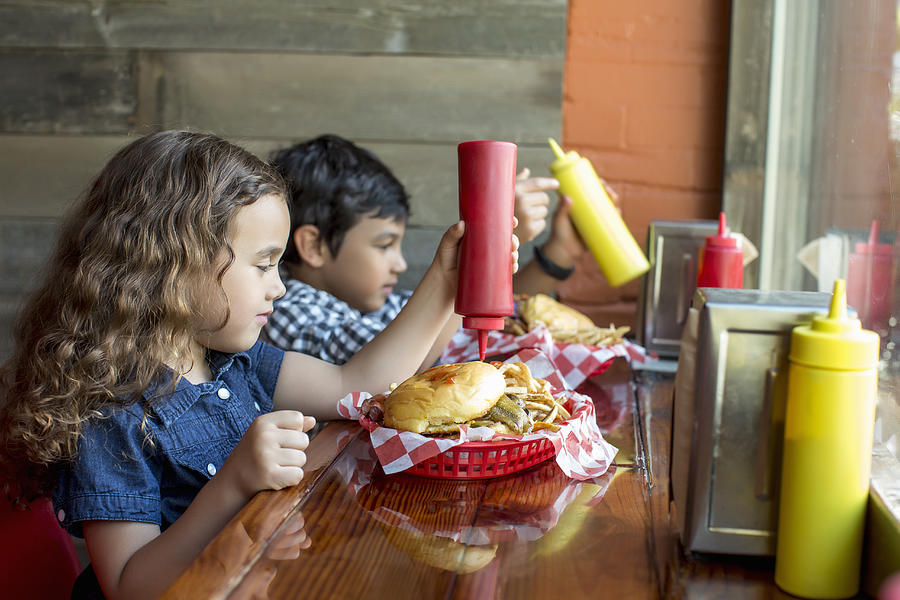 Mixed race children having burgers in restaurant Photograph by Inti St Clair
