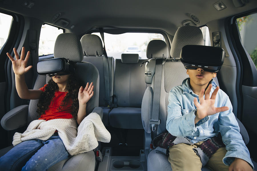 Mixed race children using virtual reality goggles in car Photograph by Inti St Clair