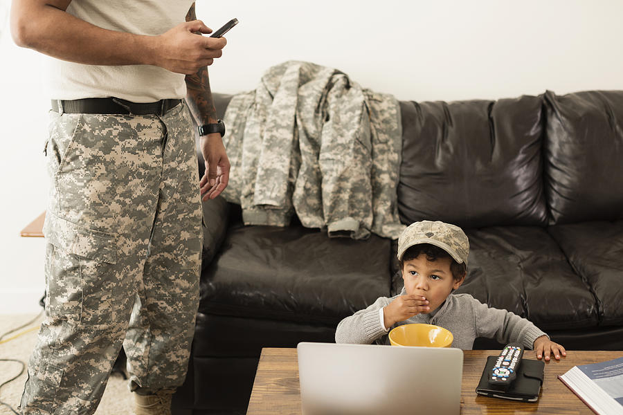 Mixed race father soldier and son relaxing in living room Photograph by Roberto Westbrook