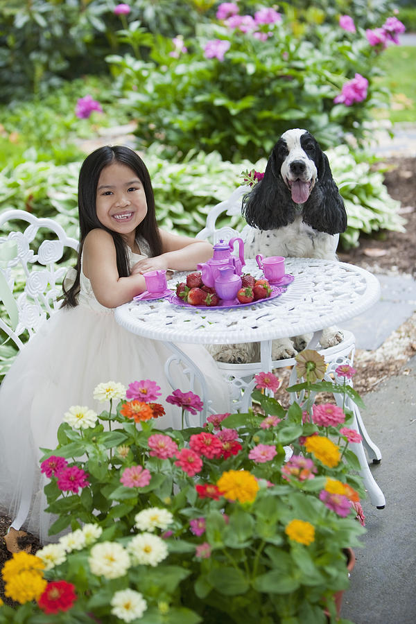 Mixed race girl and dog having tea party in backyard Photograph by Tracey Lee